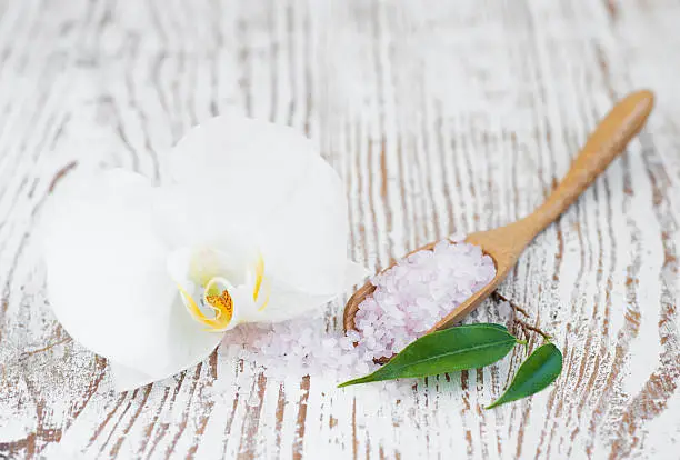 bathsalt, orchid  and green leaves on a wooden background