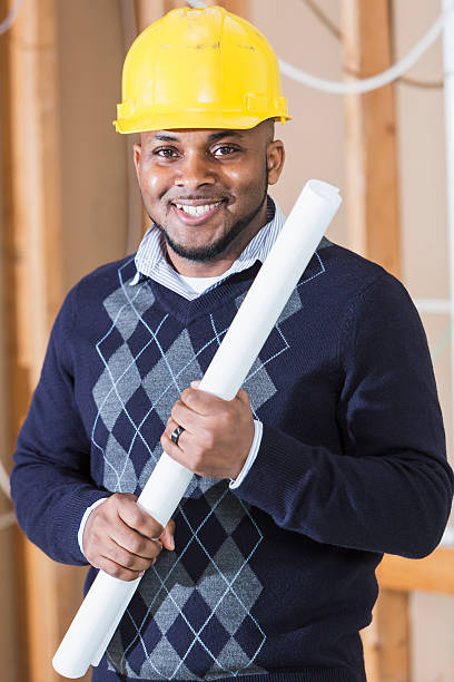 istock Black man wearing hardhat and holding floor plans 480660470