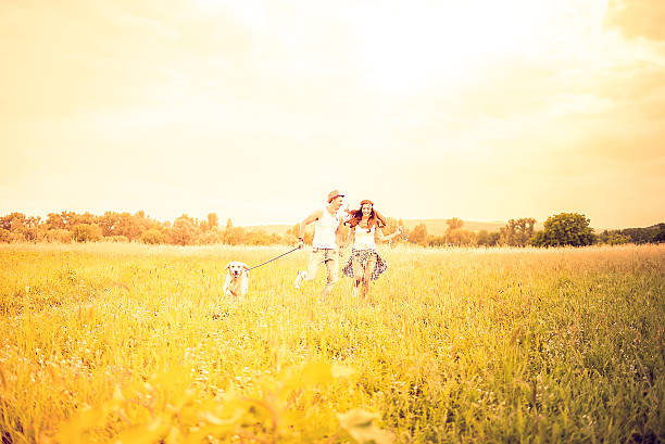 istock Couple running with their dog in field 480660532