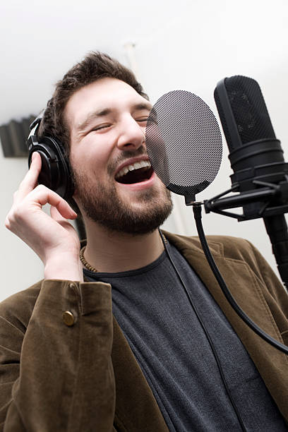 istock Caucasian Young Man in Headphones Singing into Studio Microphone 480671447