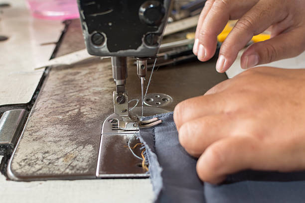 Woman hands sewn fabric repairs on sewing machine