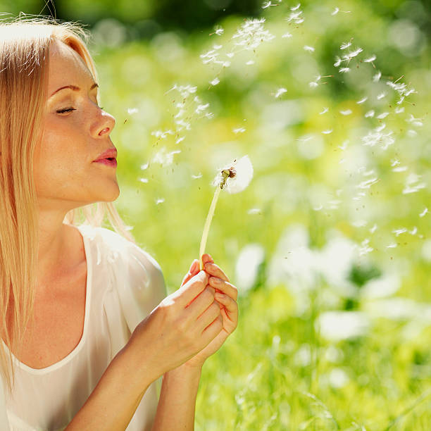 istock girl blowing on a dandelion 480681169