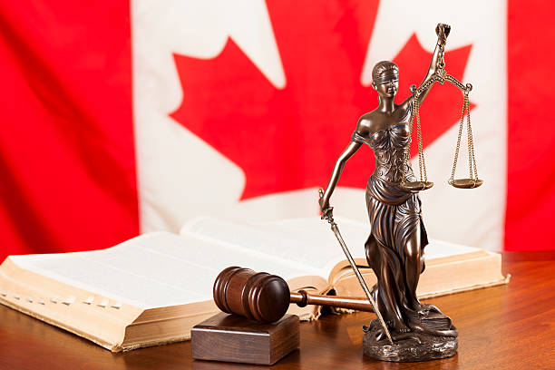 Lady justice, gavel and a law book against the national flag of Canada.