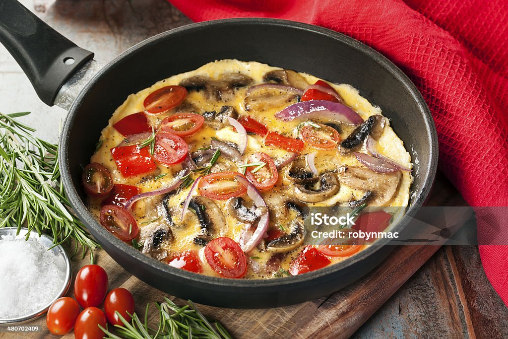 Vegetable Omelet in Skillet Vegetable omelet cooked in a skillet or frypan.  Mushrooms, capsicum, baby plum tomatoes and red onion. Omelet Stock Photo