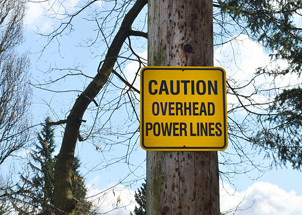 Caution Sign Close up of a caution sign regarding power lines. utility pole with power lines close up stock pictures, royalty-free photos & images