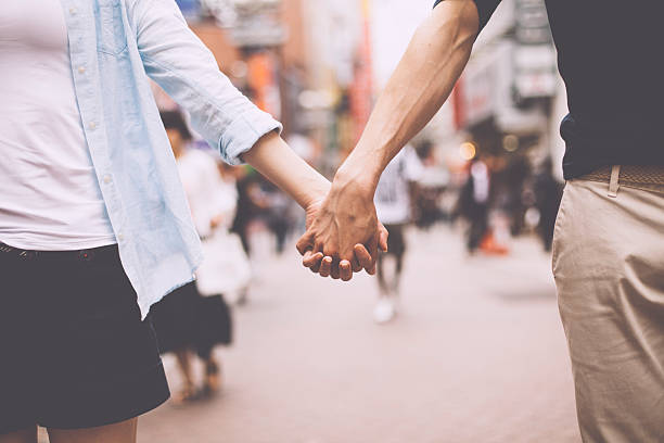 Young couple holding their hands against cityscape background. People in the image are  worn with casual clothes.  Image taken during Tokyo Istockalypse 2015