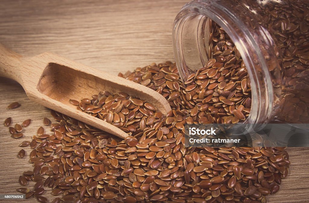 Vintage photo of linseed and glass jar Vintage photo of brown linseed, flax seeds spilling out of glass jar on wooden background, concept for healthy nutrition 2015 Stock Photo