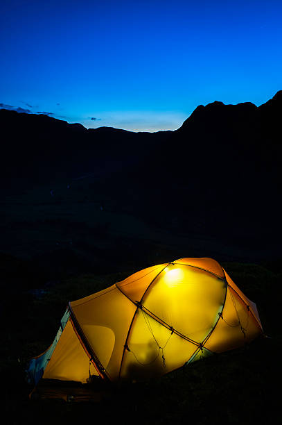 istock Warmly illuminated tent pitched high on dark dusk mountain peak 480707637