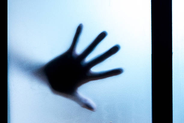 Shadow of hands behind frosted glass in the back light. stock photo