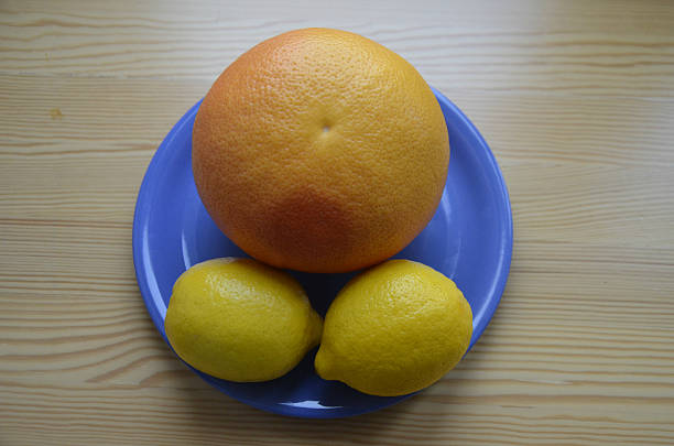 Dois limões e toranja na placa azul - fotografia de stock