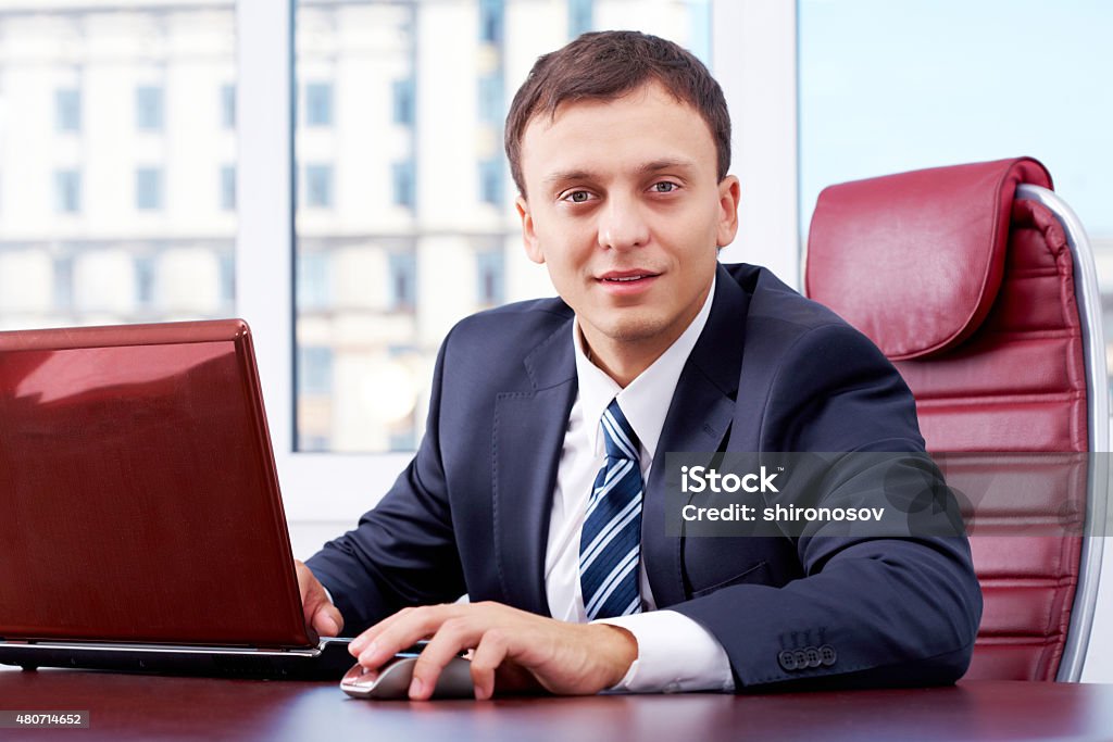 At work Portrait of smart businessman looking at camera with laptop near by 2015 Stock Photo