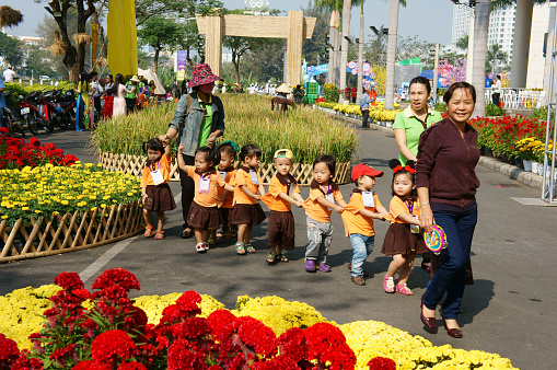Group of unidentified Asian kid with outdoor activity of preschool, little boy, girl in uniform, Vietnamese children visit park in springtime, Vietnam