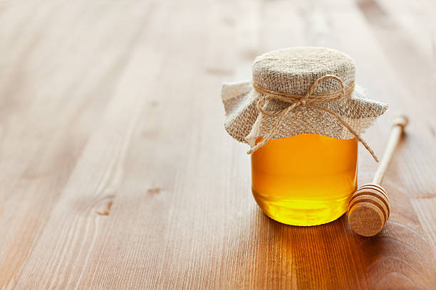 honey in jar with twine, honey dipper, lemon and ginger