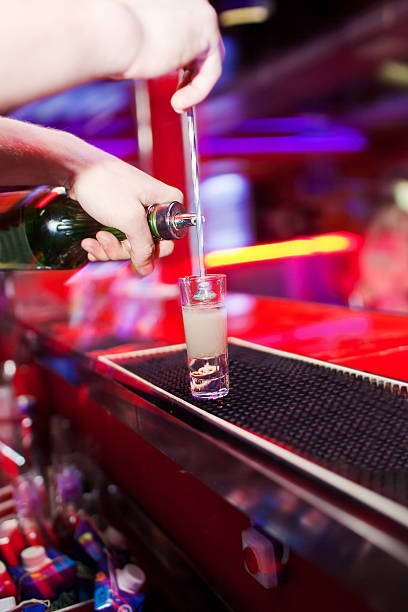 Barman's hands in interior bar are poured liquor