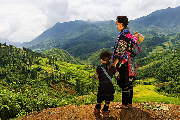 Vietnamese minority people - woman from Black Hmong Hill Tribe Black Hmong woman looking at the view & carrying her baby. Hmong Tribe is one of the largest ethnic minorities in Vietnam is the Hmong Tribe. They came from China, and now live in different regions of Vietnam. miao minority stock pictures, royalty-free photos & images