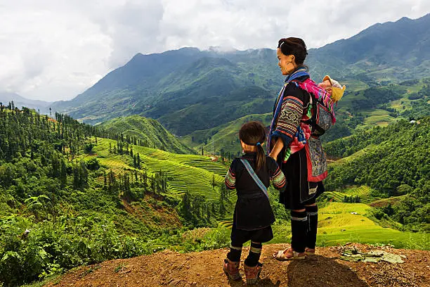 Black Hmong woman looking at the view & carrying her baby. Hmong Tribe is one of the largest ethnic minorities in Vietnam is the Hmong Tribe. They came from China, and now live in different regions of Vietnam.
