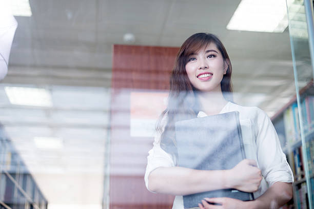 istock asian beautiful female student holding book in library portrait 480726766