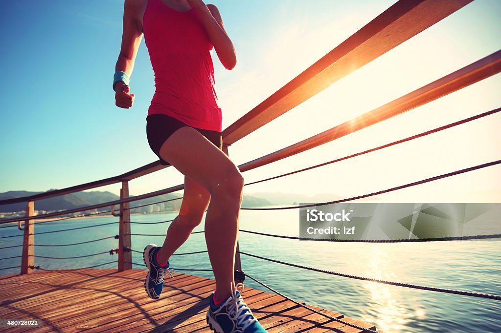 young fitness woman legs running on seaside wooden boardwalk 2015 Stock Photo