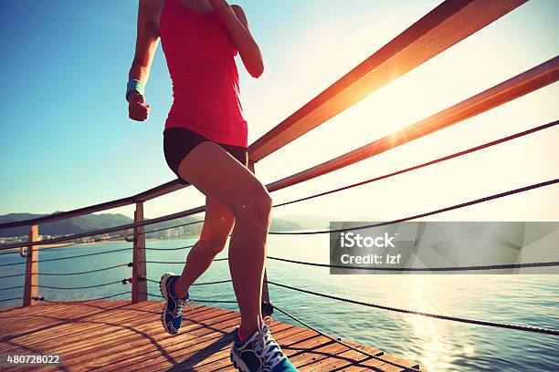 Young Fitness Woman Legs Running On Seaside Wooden Boardwalk Stock Photo - Download Image Now