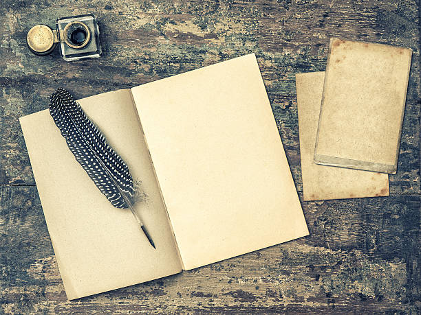 Open book, antique writing tools feather pen and inkwell.