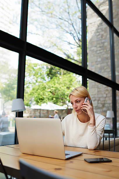 istock Business woman talk on smartphone while looking to net-book screen 480732896