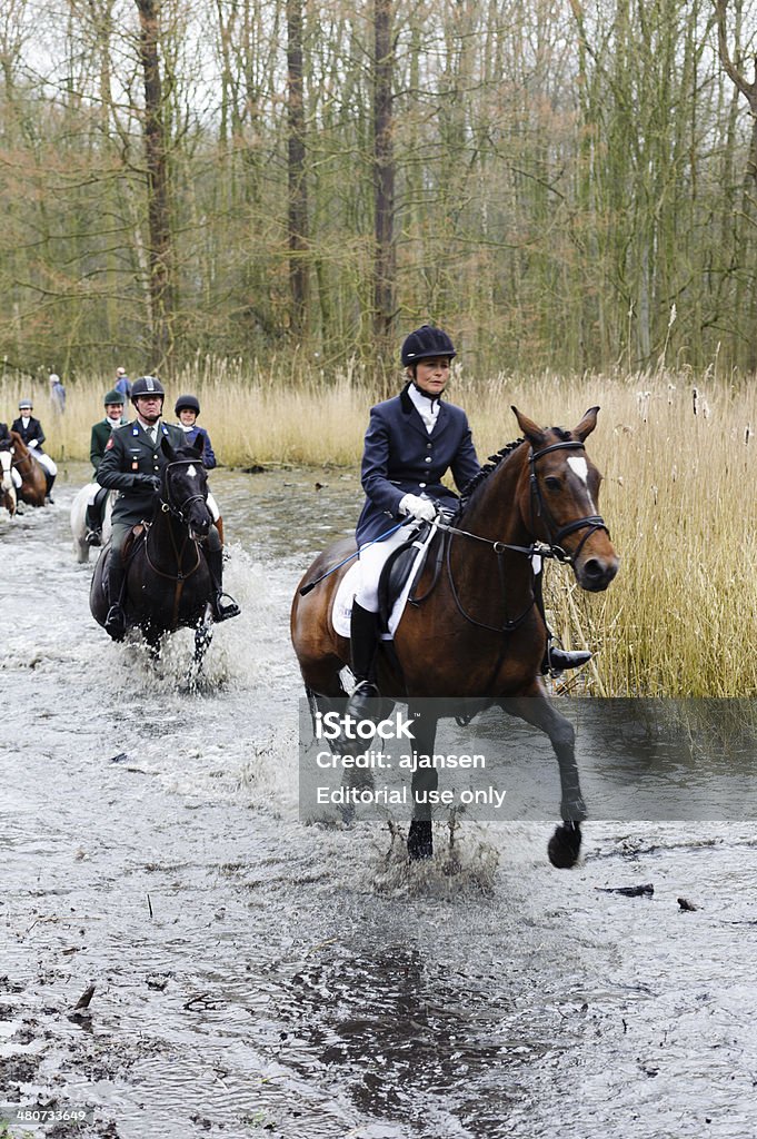 hunters riding their horses through a swamp amsterdam, netherlands - March 15, 2014: hunters riding their horses through a swamp in historic clothing during a fox hunt in the amsterdam forest England Stock Photo