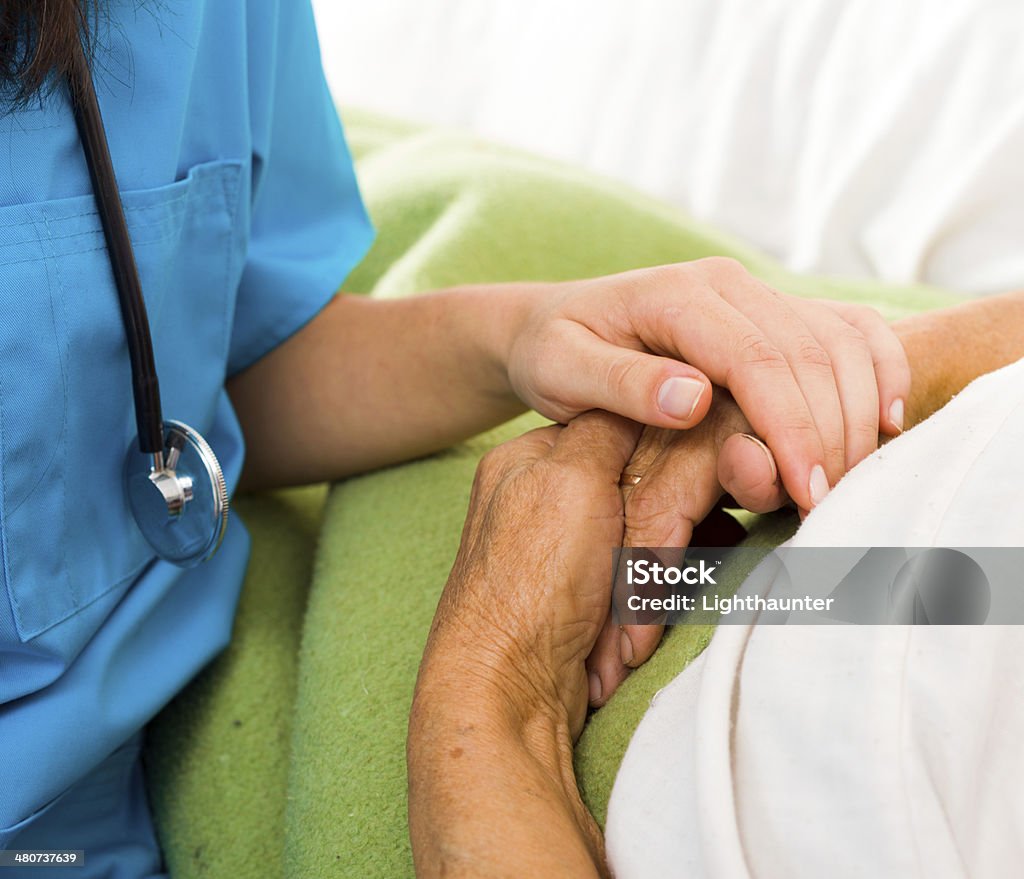 Caring Nurse Holding Hands Health care nurse holding elderly lady's hand with caring attitude. Adult Stock Photo