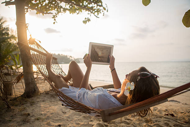 istock Attractive woman with digital tablet on hammock 480738239