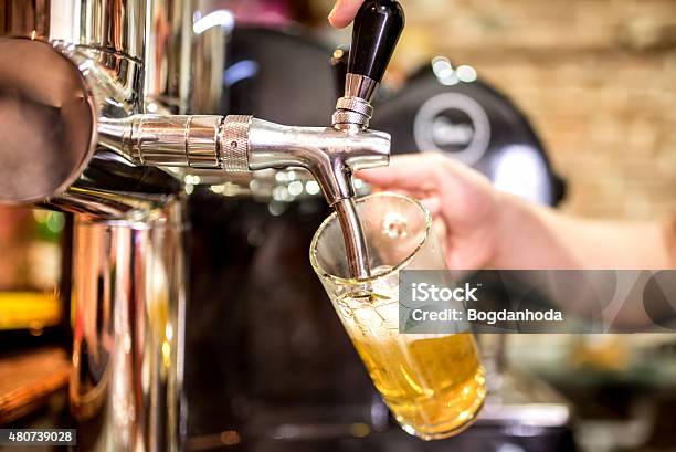 Barman Hand At Beer Tap Pouring Draught Lager Beer Stock Photo - Download Image Now - 2015, Alcohol - Drink, Amber