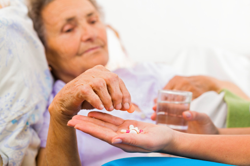 Nurse giving medication to elderly patient in nursing home.