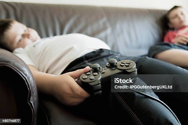 Boys Dormir En El Sofá Mientras Se Sostiene De Consolas De Juegos Foto de stock y más banco de imágenes de Gordo - Complexión