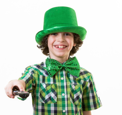 Young male boy turns off or on the TV during St. Patrick day celebrations