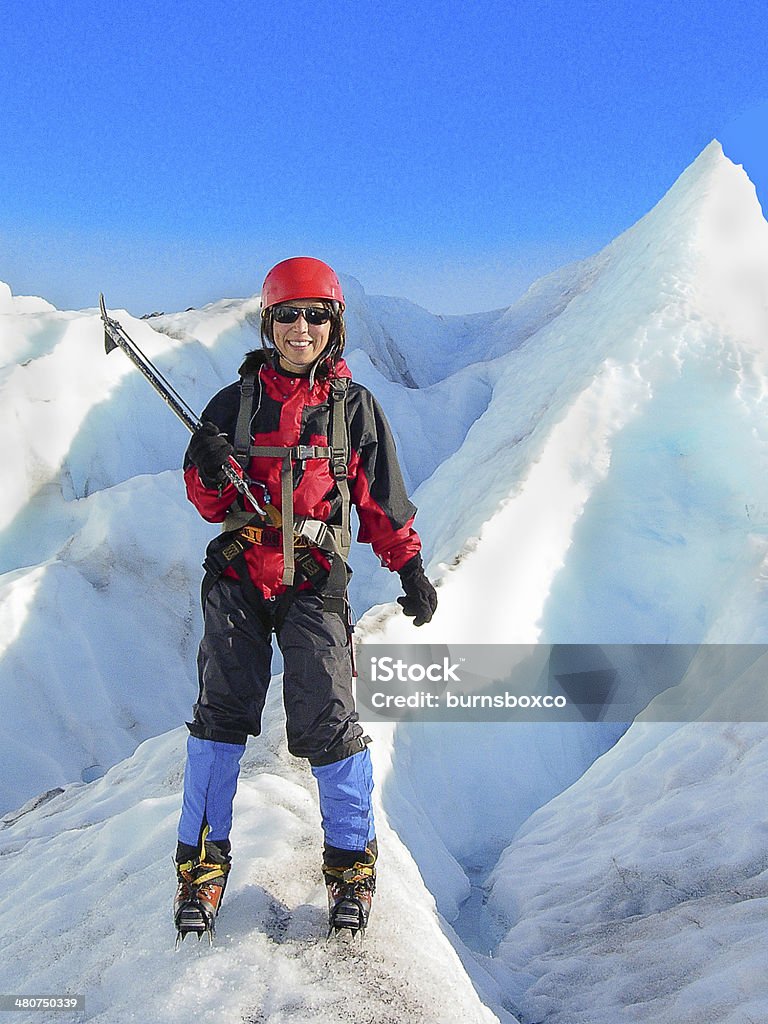Asian Woman Ice Climber on Mountain Peak Asian woman ice climber on Mountain Peak with Peak in background wearing helmet and ice axe. Alaska - US State Stock Photo