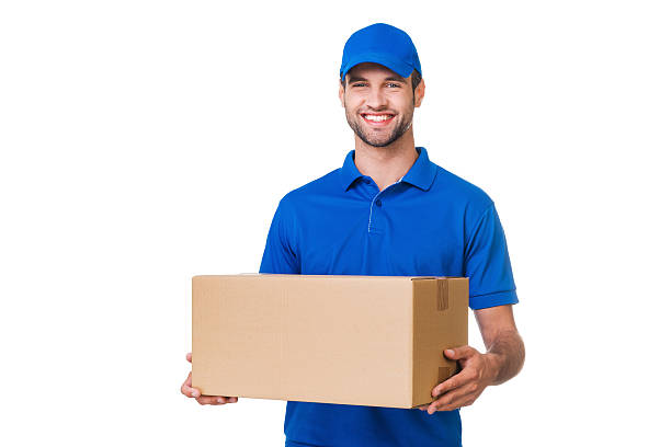 Cheerful delivery man. Happy young courier holding a cardboard box and smiling while standing against white background delivery person stock pictures, royalty-free photos & images