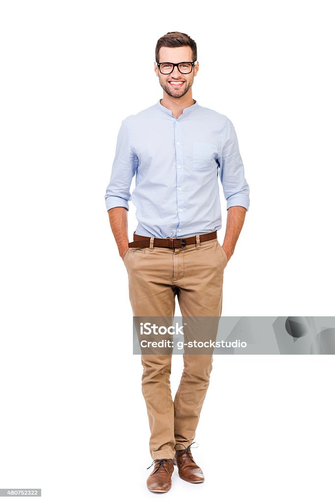 Confident in any situation. Happy young man holding hands in pockets and looking at camera while standing against white background Full Length Stock Photo