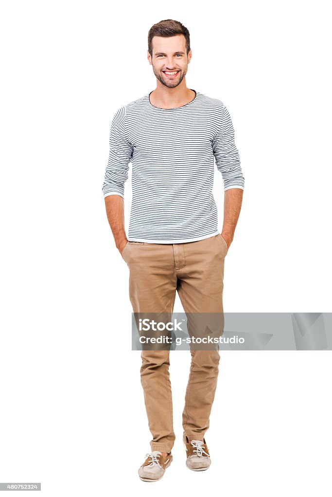 Confident and stylish. Full length of cheerful young man holding hands in pockets and looking at camera while standing against white background Men Stock Photo