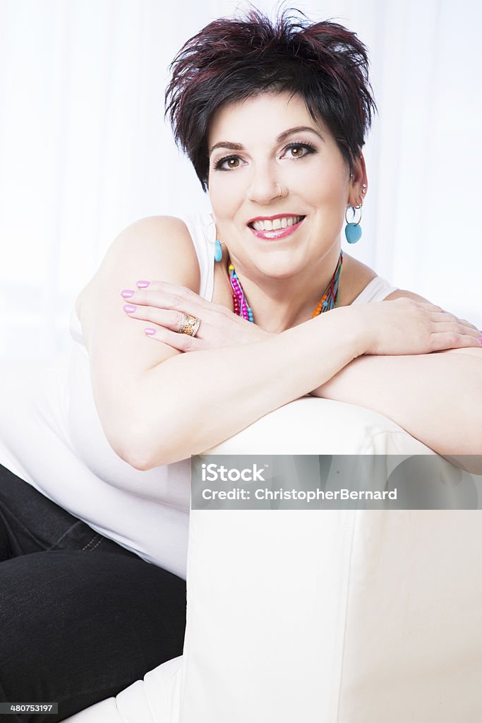 Smiling mature woman sitting on couch Woman's beauty portrait on couch Pixie Cut Stock Photo