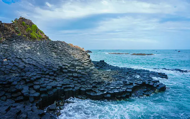 Tourists explore the Giant's Causeway, Ganh Da Dia, TuyHoa, PhuYen, VietNam. Huge basalt rocks rise out of the sea on coast