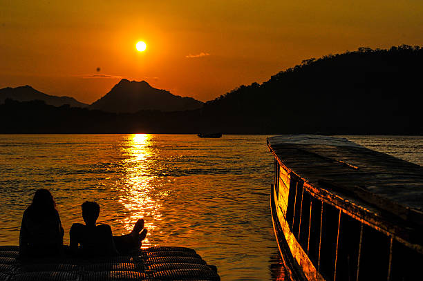 piękny zachód słońca i dwóch miłośników w pobliżu rzeka mekong - luang phabang laos thailand mekong river zdjęcia i obrazy z banku zdjęć