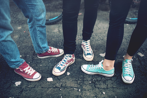 Young rebel teenagers wearing casual sneakers, walking on dirty concrete