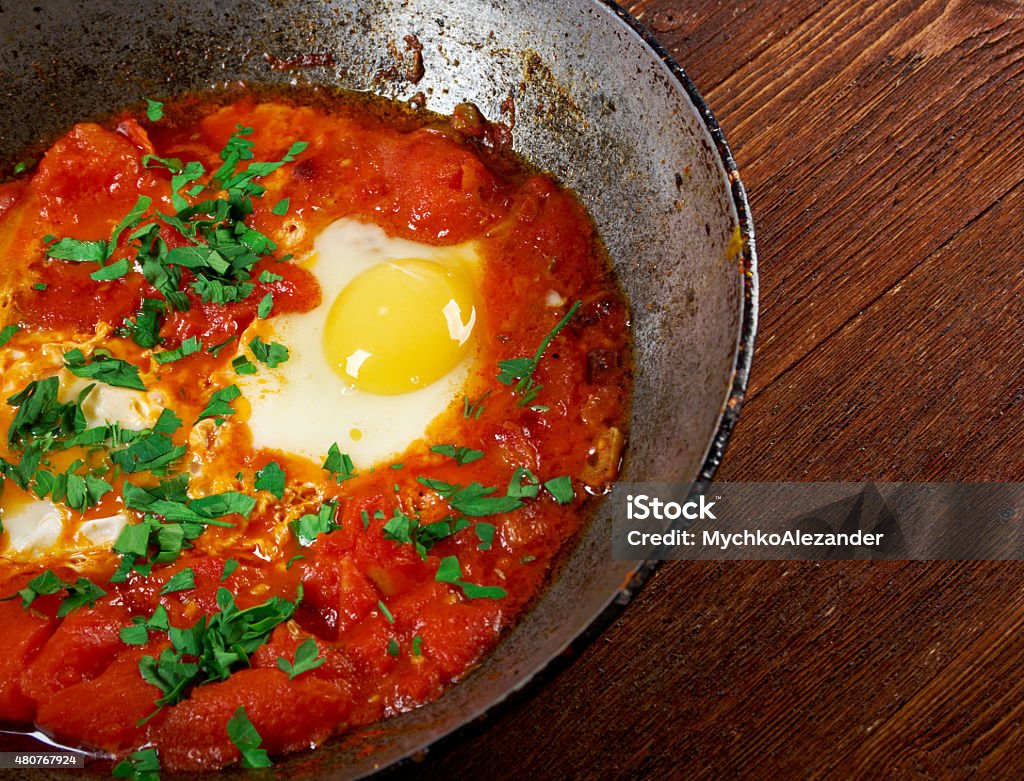 Shakshuka Shakshuka -dish of eggs poached in a sauce of tomatoes, chili peppers, and onions, often spiced with cumin.Moroccan, Tunisian, Libyan, Algerian, and Egyptian cuisines traditionally 2015 Stock Photo