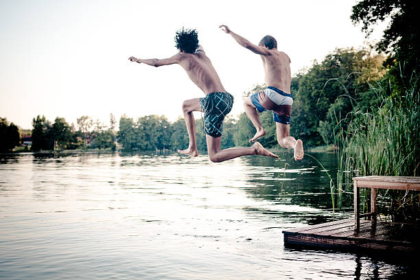 istock carefree summer day: teenagers jumping into a lake 480777777