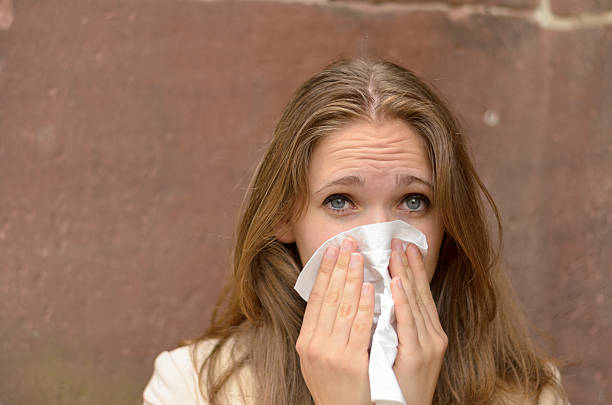 istock Young woman blowing her nose on a handkerchief 480785002