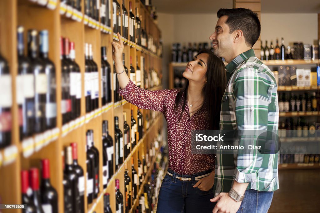 Picking up some wine at the store Young Latin couple deciding which wine to buy at the supermarket Wine Stock Photo