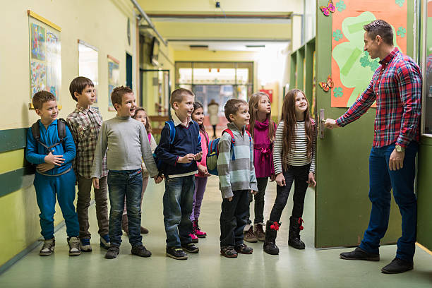 istock Happy teacher welcoming group of his elementary students. 480803620