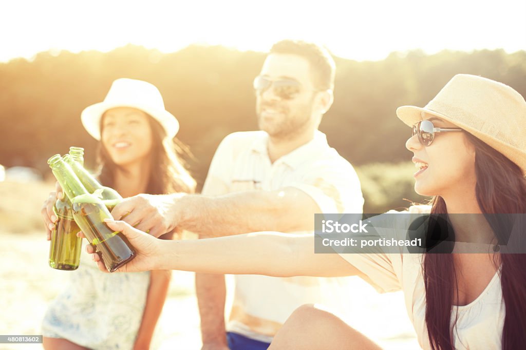 Young people having fun at beach party Young people enjoying a beach party.Two of them are wearing sunglasses. All of them holding beer bottles. 20-24 Years Stock Photo