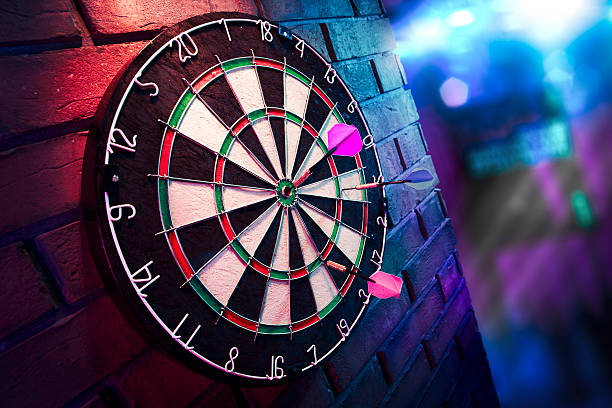 Dart board on a brick wall with dramatic lighting dartboard on a brick wall dart stock pictures, royalty-free photos & images