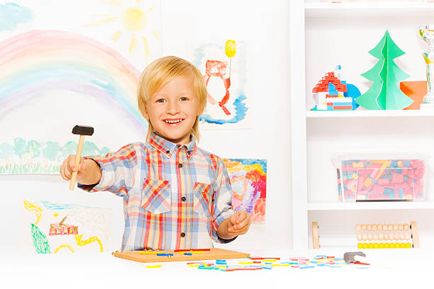 istock Happy blond boy with hammer and blocks in class 480816340