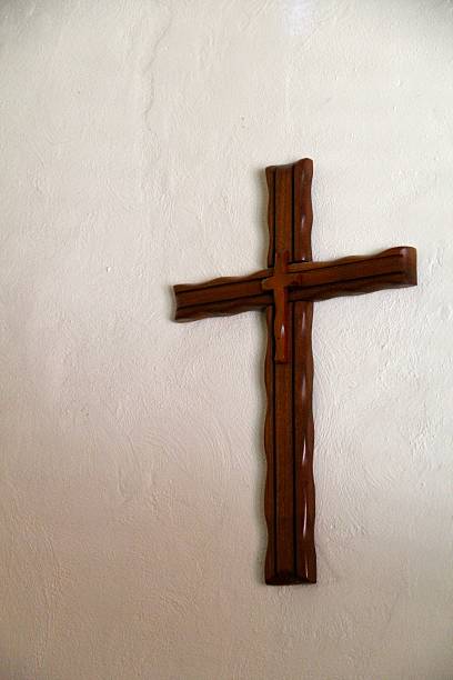istock Handmade Wooden Cross hangs on a Plaster Wall Vertical 480816757