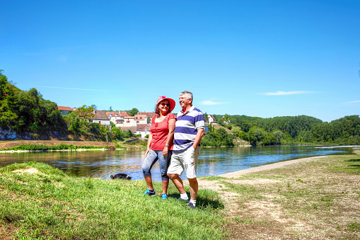 Mature couple walking dog alongside River Dordogne
